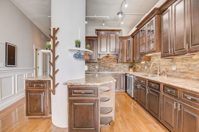 kitchen with light stone countertops, stainless steel dishwasher, a center island, and light hardwood / wood-style flooring