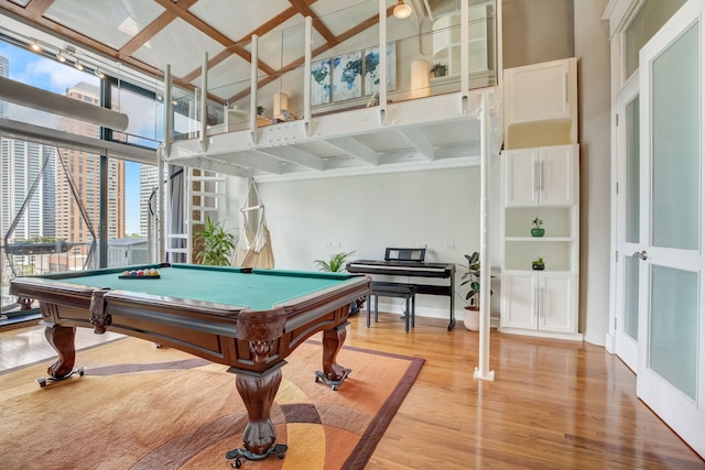 game room featuring wood-type flooring, beamed ceiling, billiards, and a high ceiling