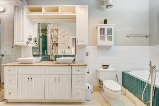 bathroom featuring a tub to relax in, tile walls, vanity, and toilet