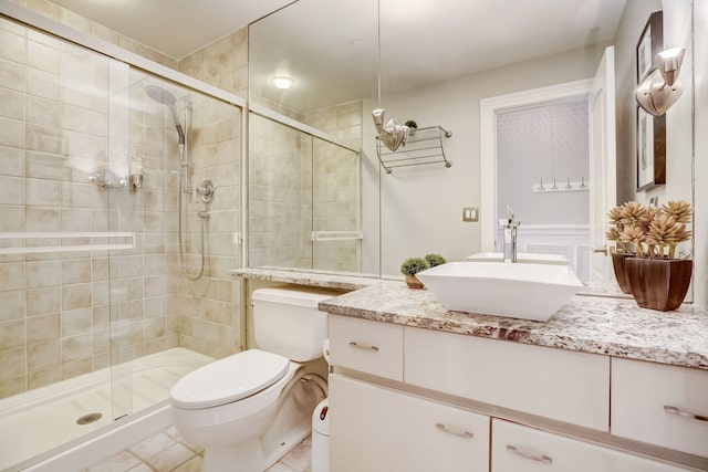 bathroom featuring vanity, toilet, tile patterned floors, and a shower with shower door