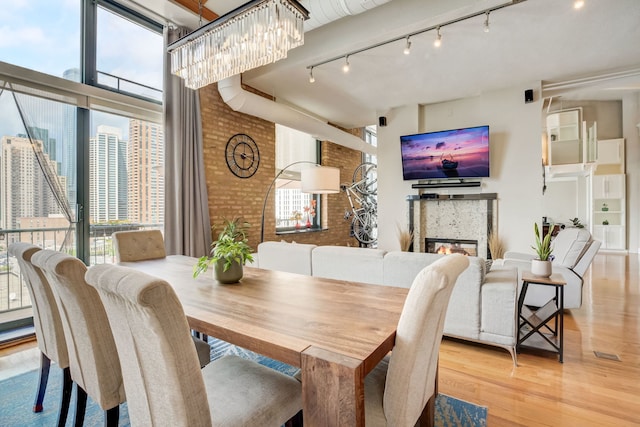 dining area featuring light wood-type flooring, a wealth of natural light, and brick wall