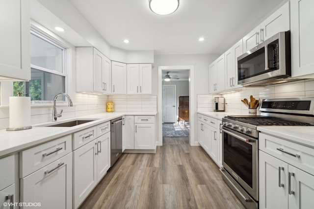 kitchen featuring stainless steel appliances, white cabinets, light hardwood / wood-style floors, and ceiling fan