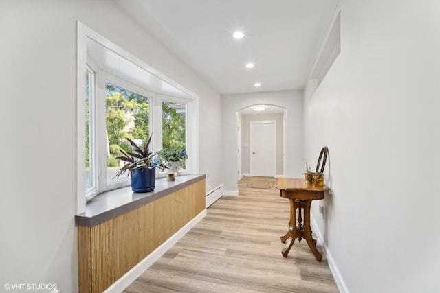 hall with a baseboard radiator and light hardwood / wood-style floors