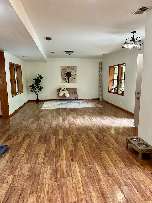 unfurnished living room with an inviting chandelier and hardwood / wood-style floors