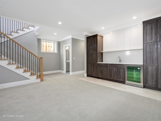 unfurnished living room with wine cooler, ornamental molding, wet bar, and light carpet