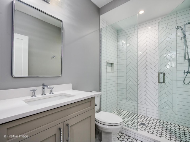 bathroom with vanity, a shower with door, and toilet