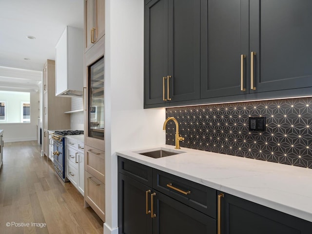 kitchen featuring sink, light hardwood / wood-style flooring, double oven range, backsplash, and light stone countertops