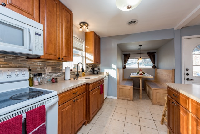 kitchen with light tile patterned flooring, tasteful backsplash, sink, hanging light fixtures, and white appliances