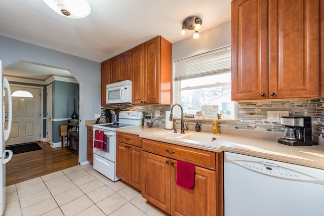 kitchen with ornamental molding, sink, white appliances, light hardwood / wood-style flooring, and backsplash