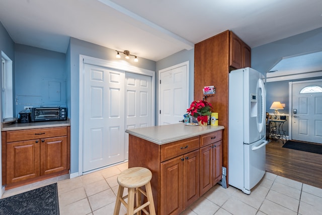 kitchen featuring light hardwood / wood-style flooring, white fridge with ice dispenser, kitchen peninsula, and a kitchen breakfast bar