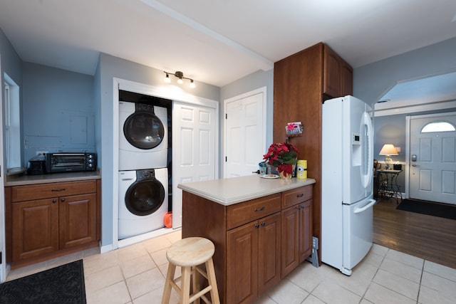 kitchen with light hardwood / wood-style floors, stacked washing maching and dryer, white refrigerator with ice dispenser, and kitchen peninsula