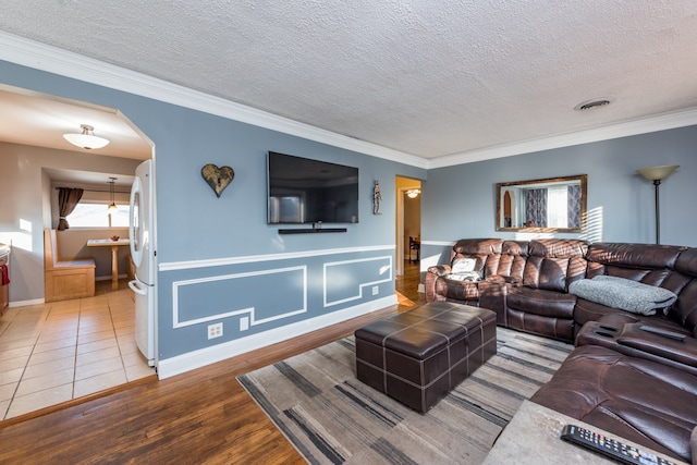 living room featuring ornamental molding, wood-type flooring, and a textured ceiling