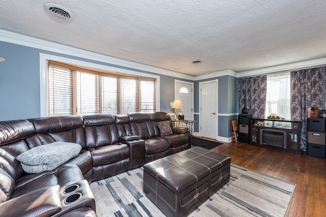 living room with hardwood / wood-style flooring, ornamental molding, and a textured ceiling