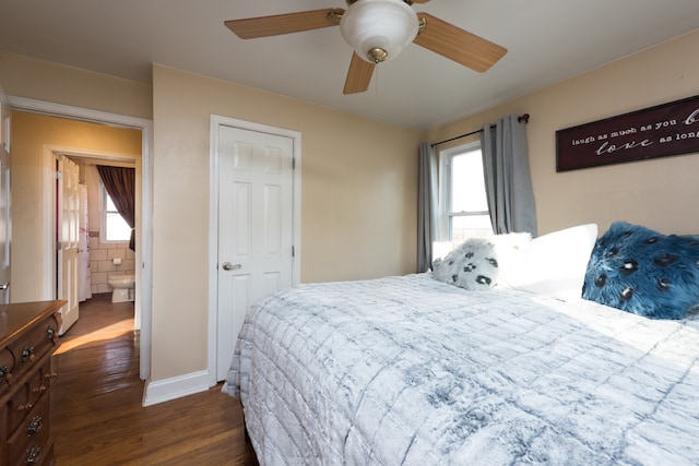 bedroom featuring ensuite bath, ceiling fan, dark hardwood / wood-style floors, and multiple windows