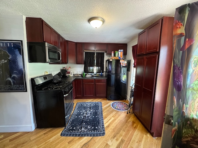 kitchen with sink, black appliances, a textured ceiling, and light wood-type flooring