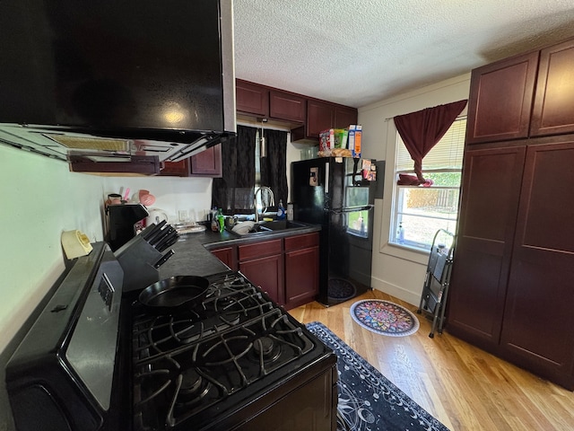 kitchen featuring sink, black appliances, light hardwood / wood-style flooring, and a textured ceiling