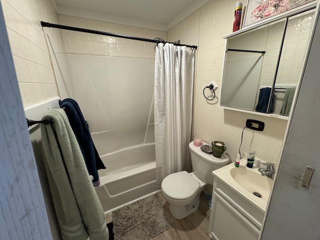 full bathroom featuring tile walls, shower / bath combo with shower curtain, toilet, vanity, and crown molding