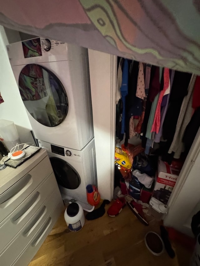 clothes washing area featuring stacked washer / drying machine and hardwood / wood-style flooring