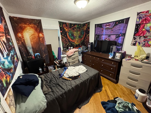 bedroom with crown molding, a textured ceiling, and light hardwood / wood-style floors