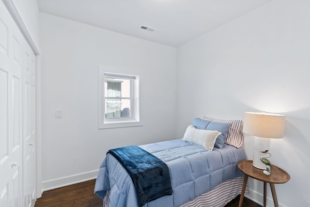 bedroom with dark hardwood / wood-style floors and a closet