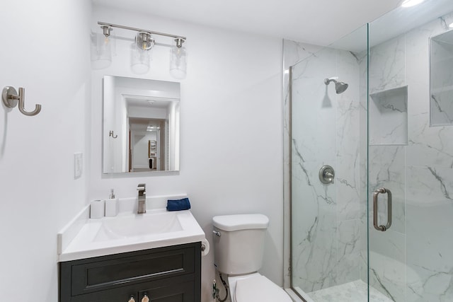 bathroom featuring a shower with door, vanity, and toilet