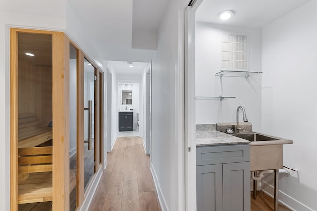 bar featuring gray cabinetry, sink, and light hardwood / wood-style flooring