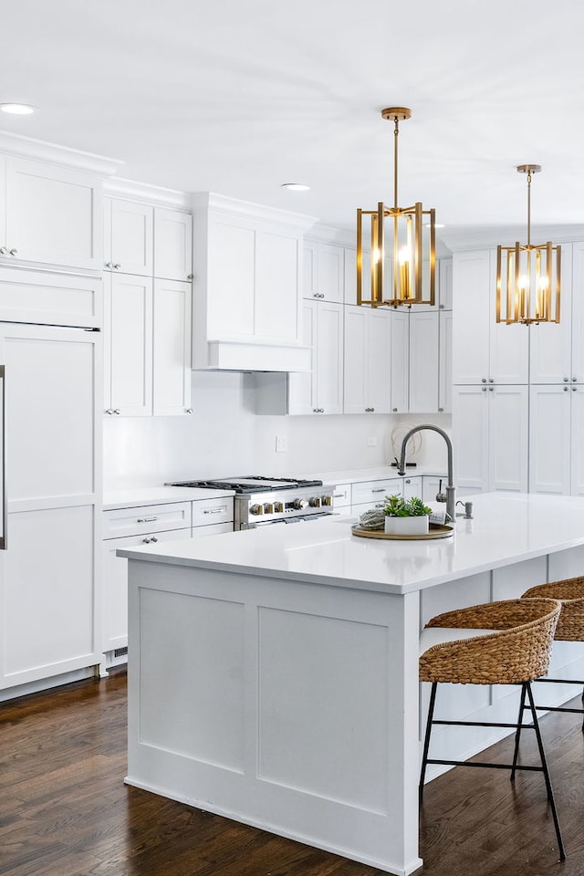 kitchen featuring hanging light fixtures, a kitchen island with sink, sink, and white cabinetry