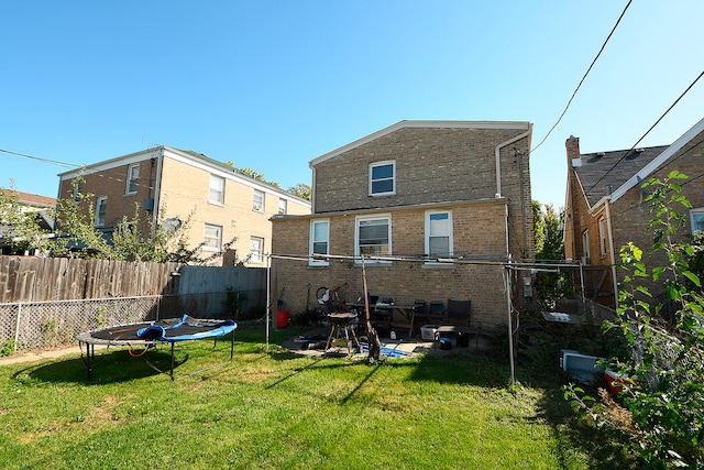 back of property featuring a patio, a trampoline, and a yard