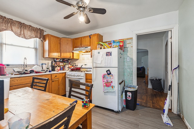 kitchen with light wood-type flooring, sink, white appliances, backsplash, and ceiling fan