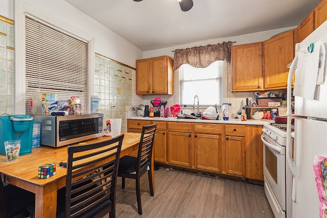 kitchen with backsplash, white appliances, dark wood-type flooring, and sink