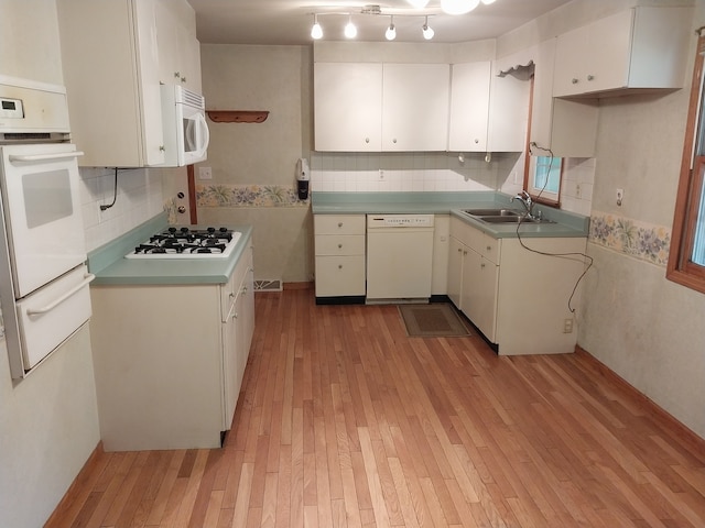 kitchen with light hardwood / wood-style floors, sink, white cabinetry, backsplash, and white appliances