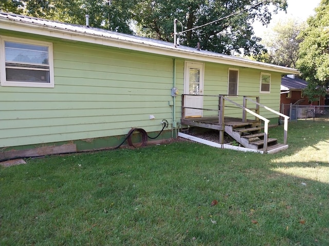rear view of house featuring fence, metal roof, and a lawn