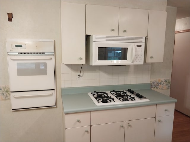 kitchen with backsplash, white appliances, dark wood-type flooring, and white cabinets