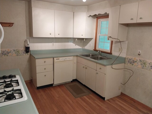 kitchen featuring white appliances, decorative backsplash, a sink, and wood finished floors