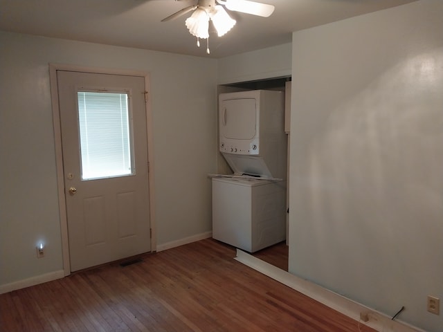 laundry room featuring ceiling fan, hardwood / wood-style flooring, and stacked washing maching and dryer