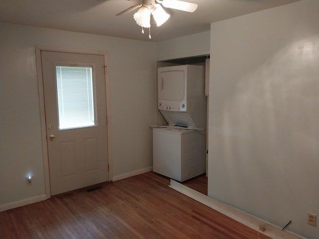 laundry room featuring baseboards, ceiling fan, stacked washer / dryer, laundry area, and wood finished floors