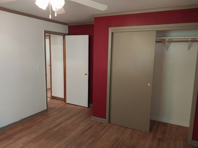 unfurnished bedroom featuring wood-type flooring, a closet, ornamental molding, and ceiling fan