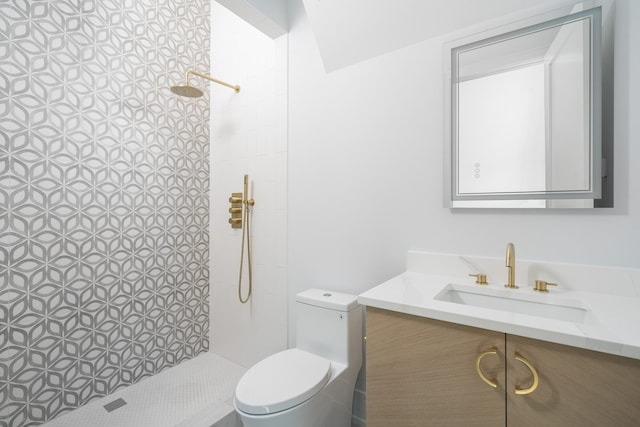 bathroom featuring a tile shower, vanity, and toilet