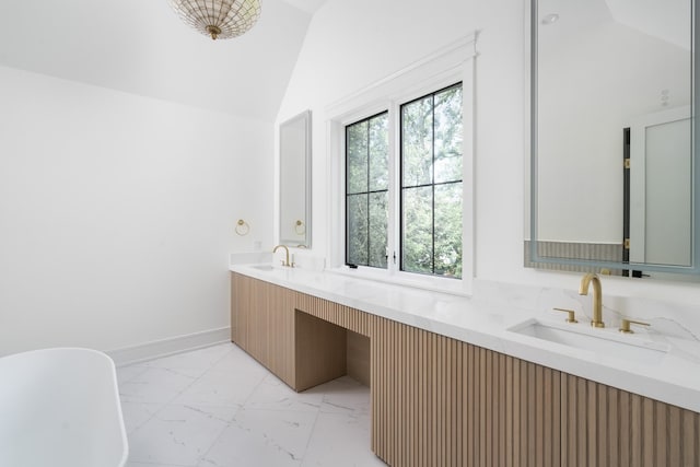 bathroom with vanity, a bathing tub, and vaulted ceiling