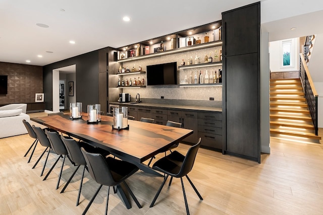 bar with light hardwood / wood-style flooring, decorative backsplash, and sink