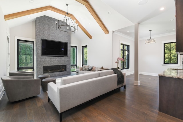 living room featuring beamed ceiling, ornamental molding, dark wood-type flooring, a chandelier, and a large fireplace