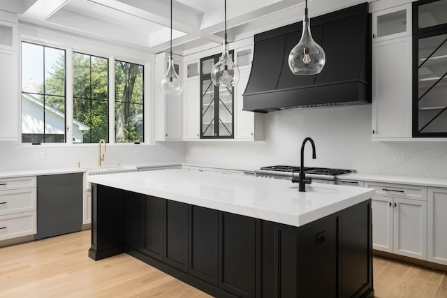 kitchen with light hardwood / wood-style floors, sink, an island with sink, and white cabinets