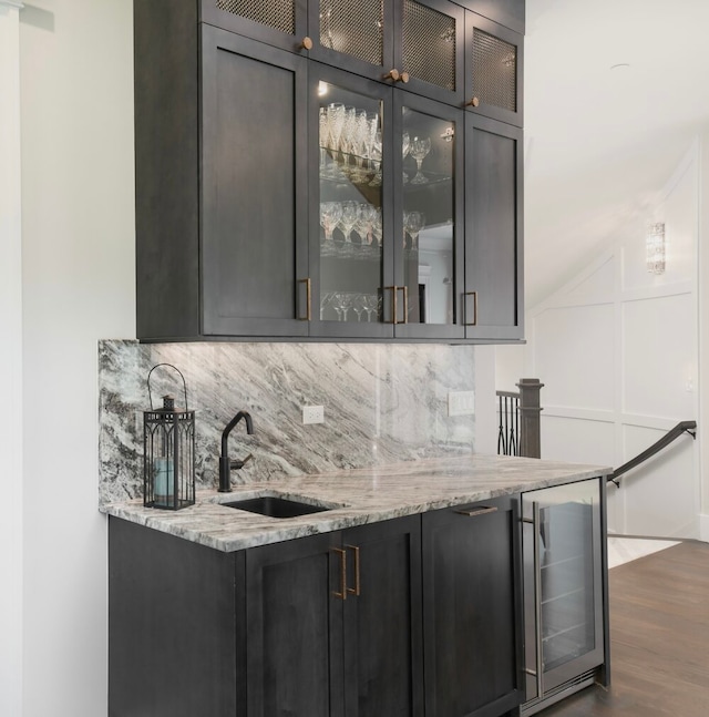 bar featuring dark hardwood / wood-style floors, beverage cooler, sink, and light stone counters