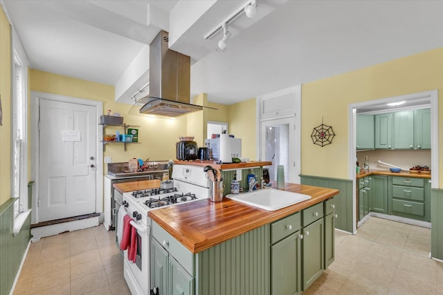 kitchen with sink, island exhaust hood, green cabinetry, and gas range gas stove