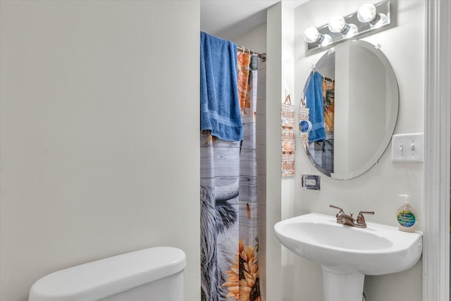 bathroom with sink, curtained shower, and toilet