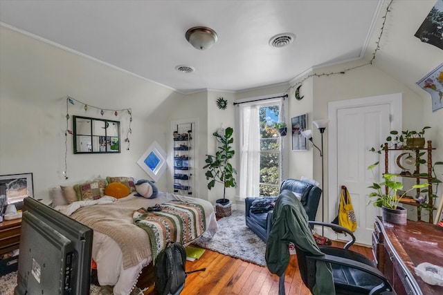 bedroom featuring hardwood / wood-style flooring, ornamental molding, and lofted ceiling