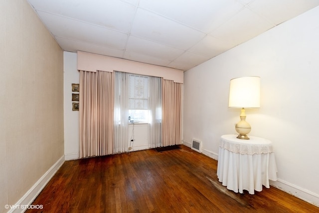 spare room featuring a paneled ceiling and dark hardwood / wood-style flooring