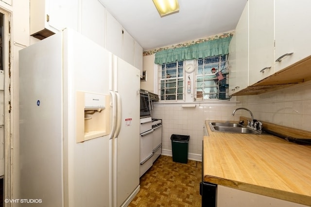 kitchen with dark parquet floors, white fridge with ice dispenser, sink, tile walls, and white cabinetry