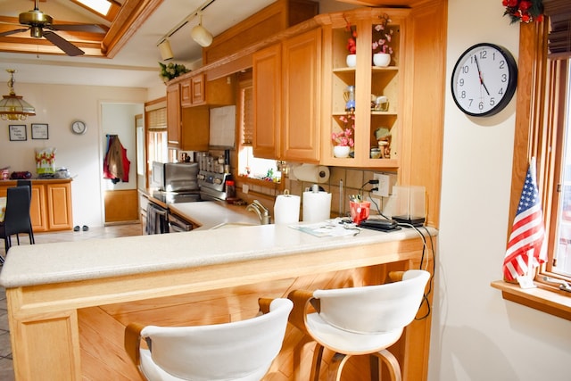 kitchen with kitchen peninsula, a kitchen bar, and ceiling fan