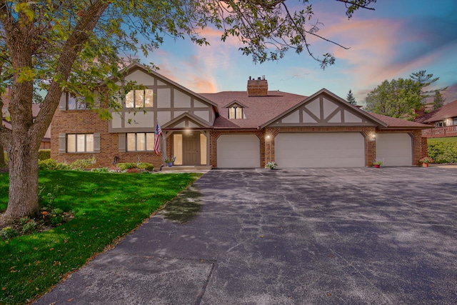 tudor home featuring a garage and a lawn